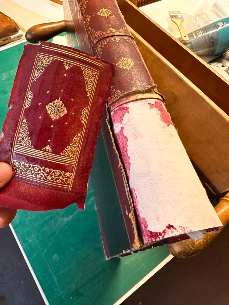 Dos d’une reliure rouge dorée et caisson façonné à l’identique pour remplacer une partie manquante.