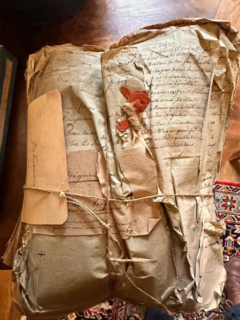 Liasse de documents manuscrits anciens avec des sceaux rouges, maintenue par des ficelles.